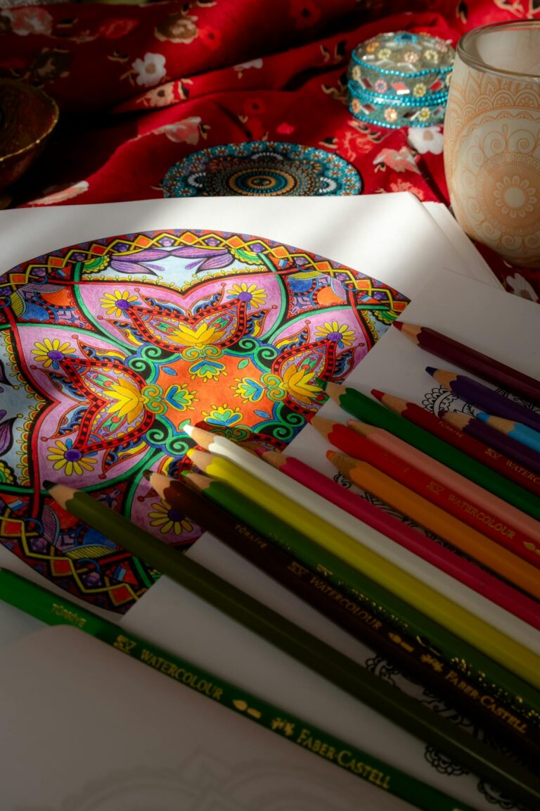 Intricate mandala art with colorful pencils on a patterned background in natural light.