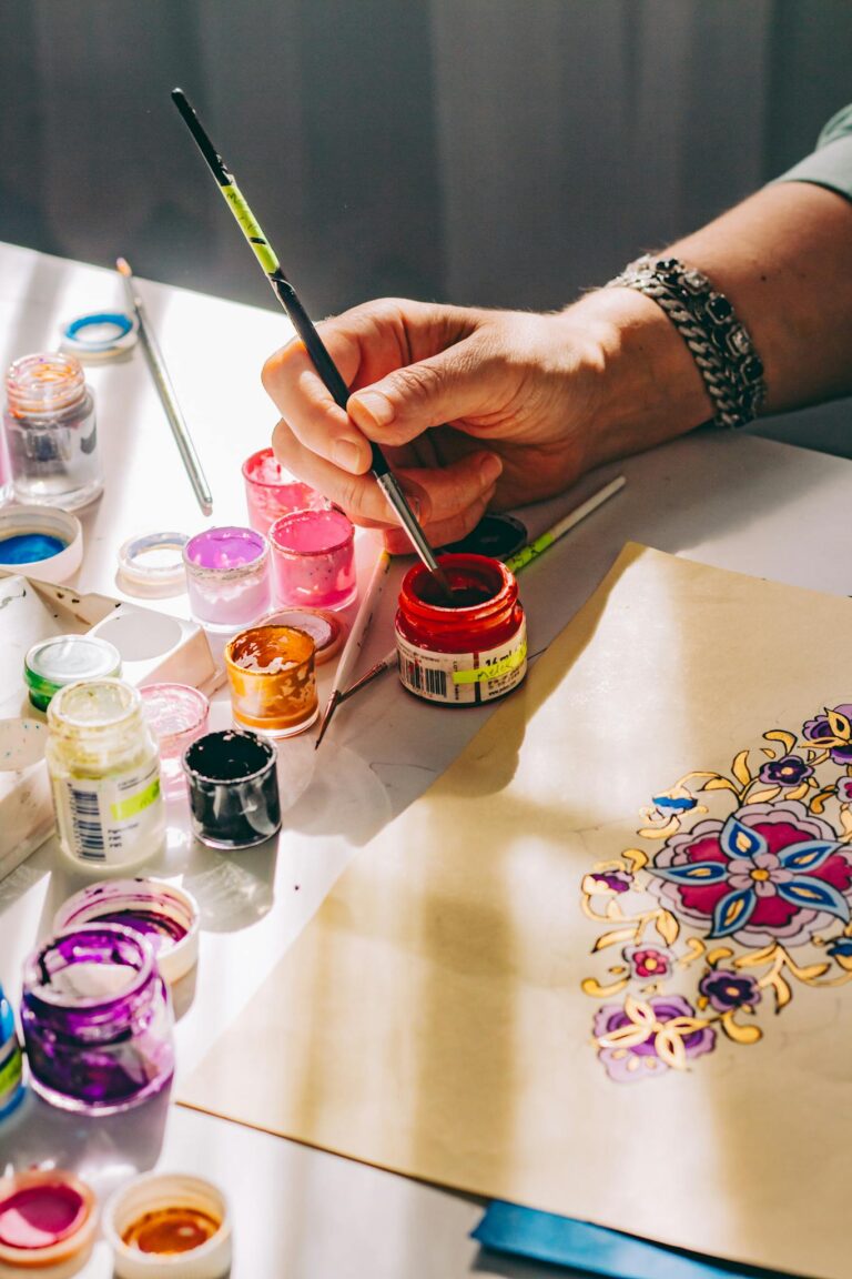 Vibrant mandala artwork being painted with various colorful paints in natural light.