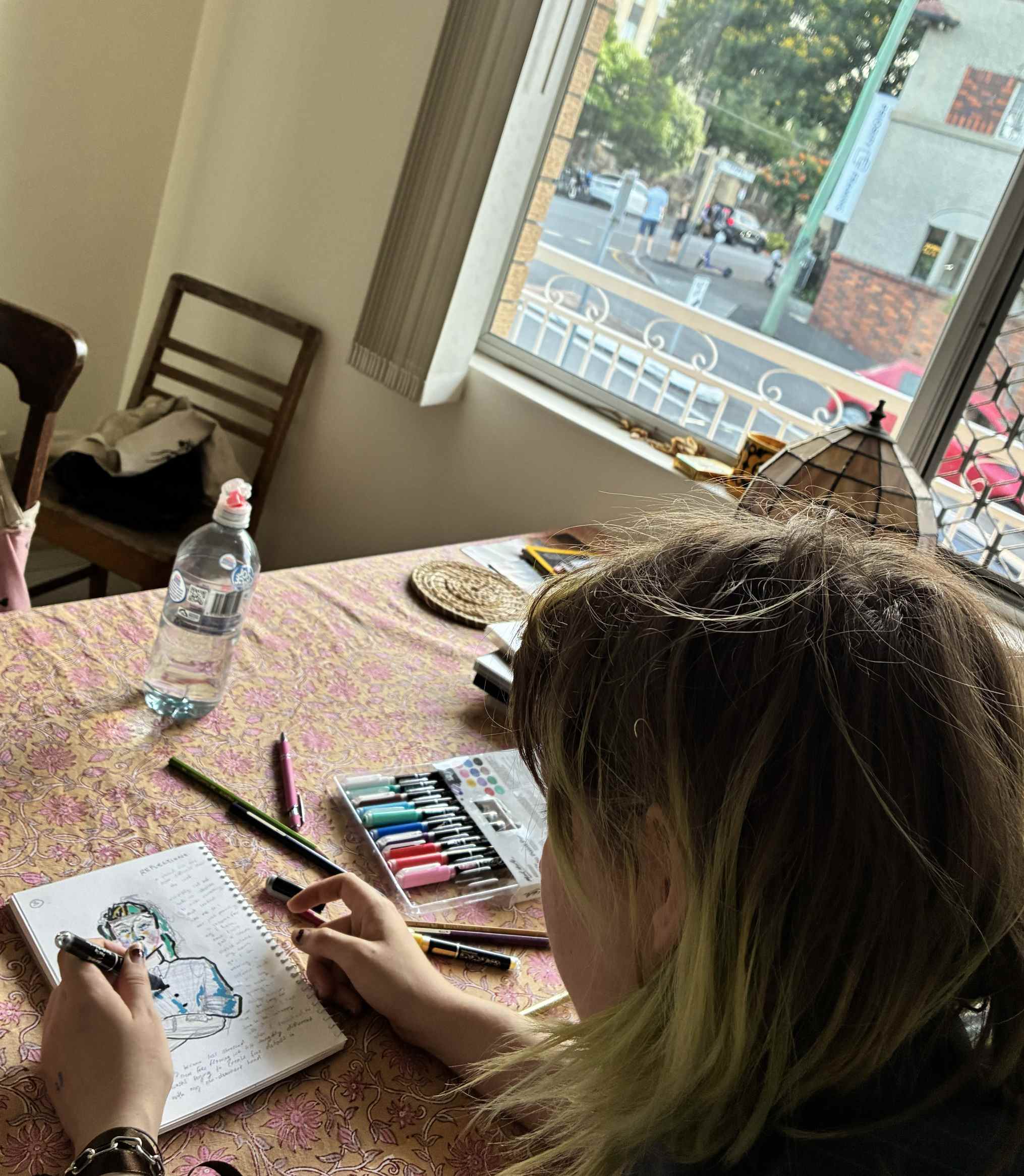 Person coloring intricate mandala design, focused relaxation with coffee mug.